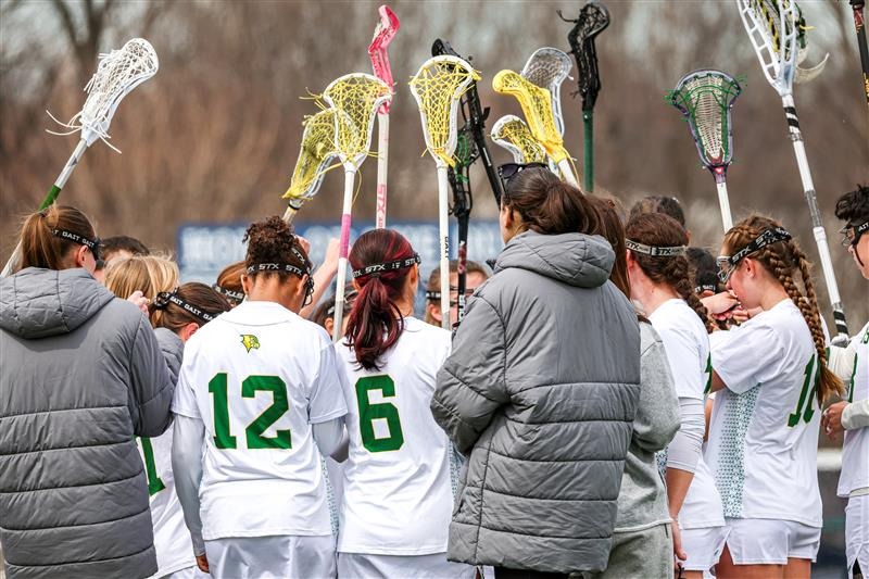 Felician Women's Lacrosse in a huddle with their sticks up