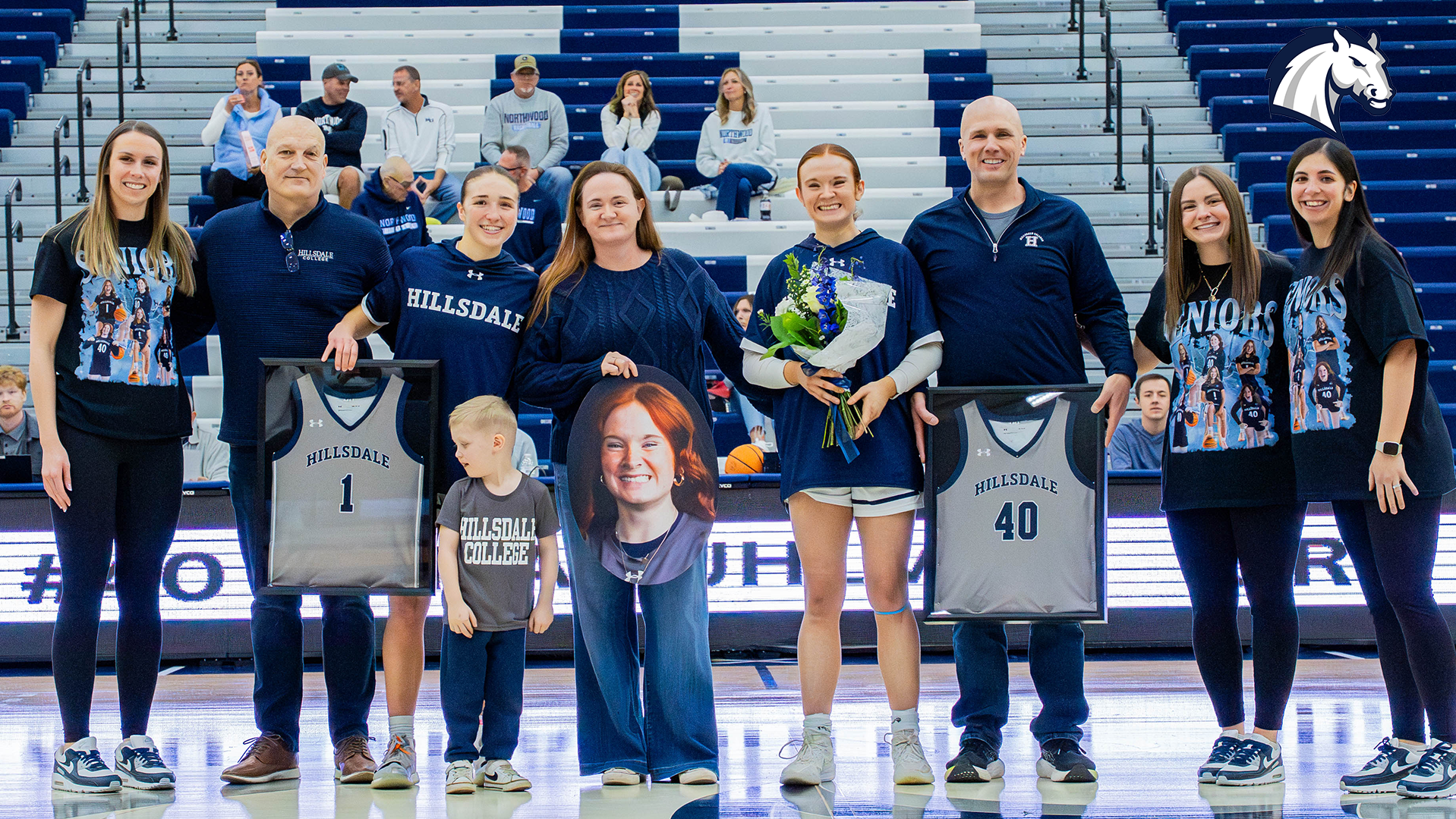 Seniors Emma Ruhlman and Payton Adkins pose with their families during Hillsdale's 2026 senior day celebration on Feb. 28.