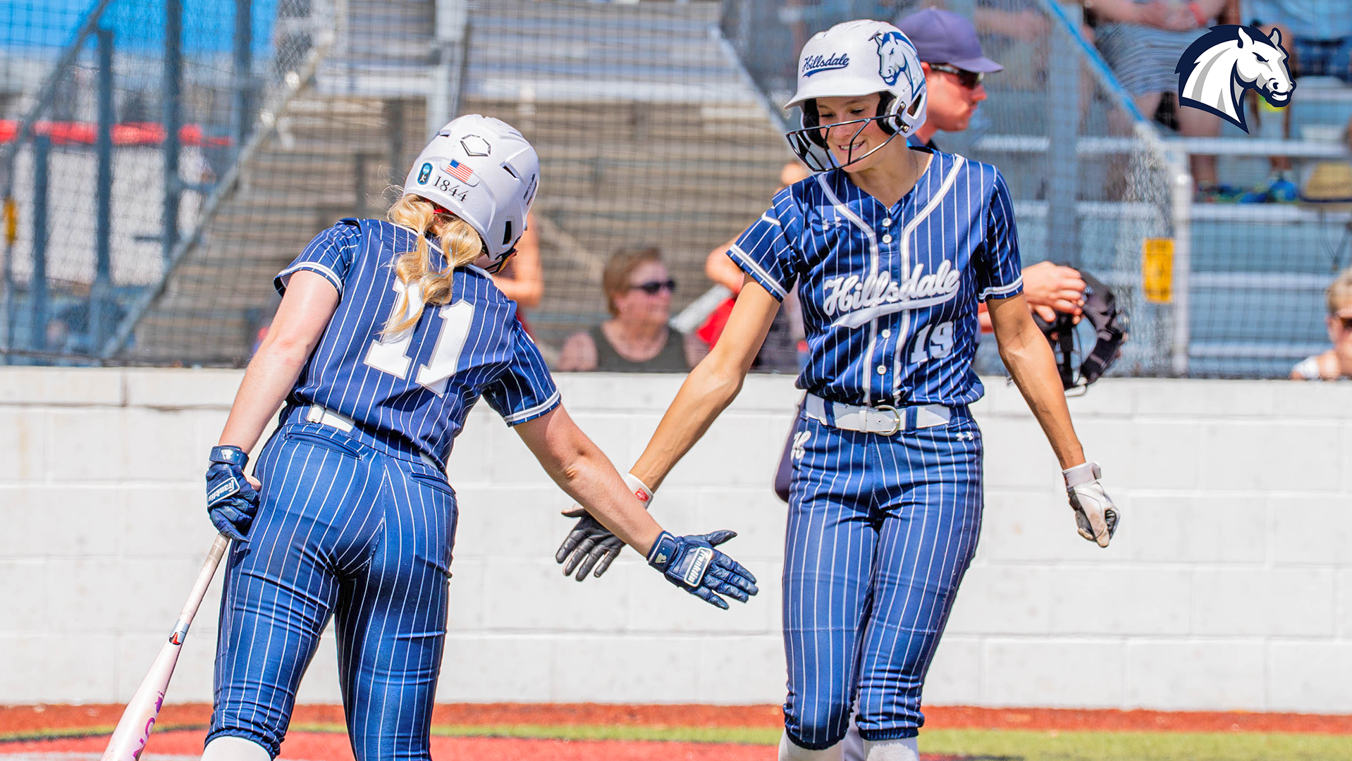 Hillsdale's Sydney Davis (left) congratulates teammate Ronnie Craft after scoring a run against Lewis during a game on March 15, 2026 in Viera, Florida.
