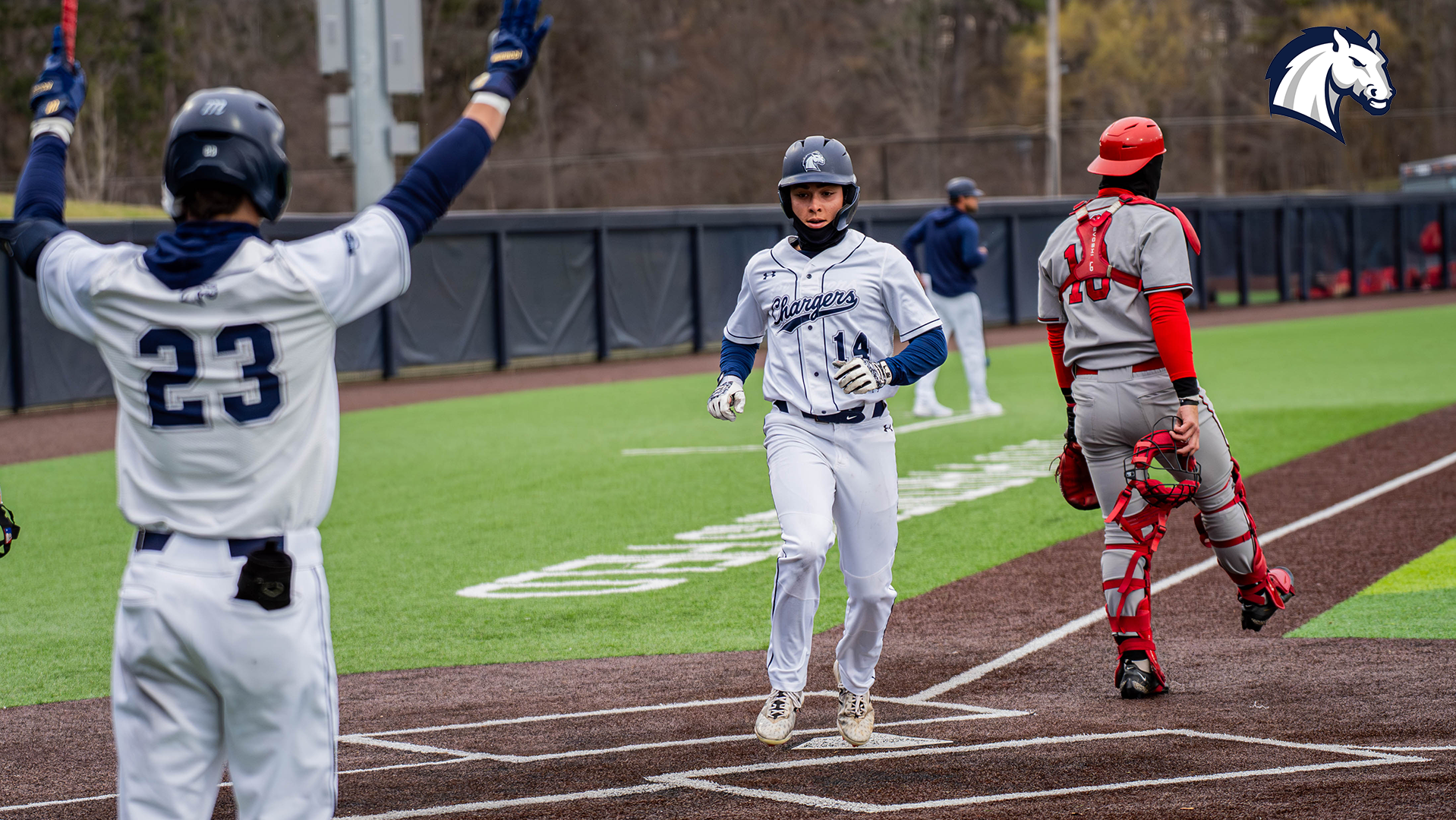 Hillsdale's Tyler Turner (left) cheers Jake Figman across home plate as Hillsdale scores in an April 1, 2026 contest against Davenport.