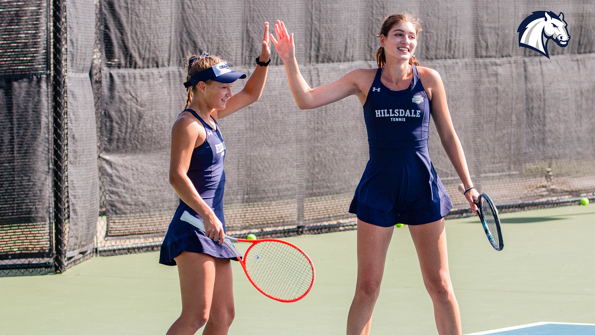 Hillsdale's Esther Sura (left) and Julia Zlateva high-five after winning a point in doubles play at the Chargers' Summer Invitational in September of 2025.
