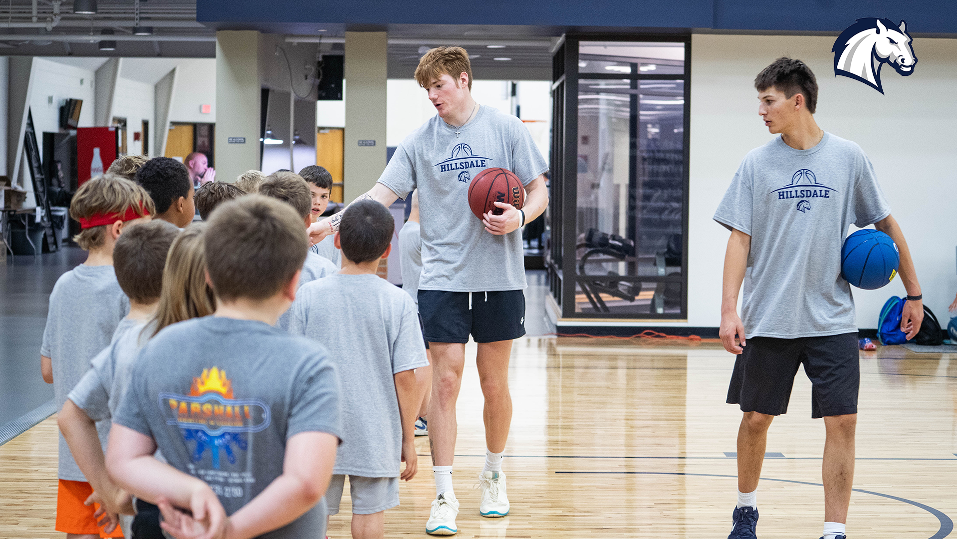 Hillsdale College men's basketball players work with campers during the 2025 Youth Basketball Camp.