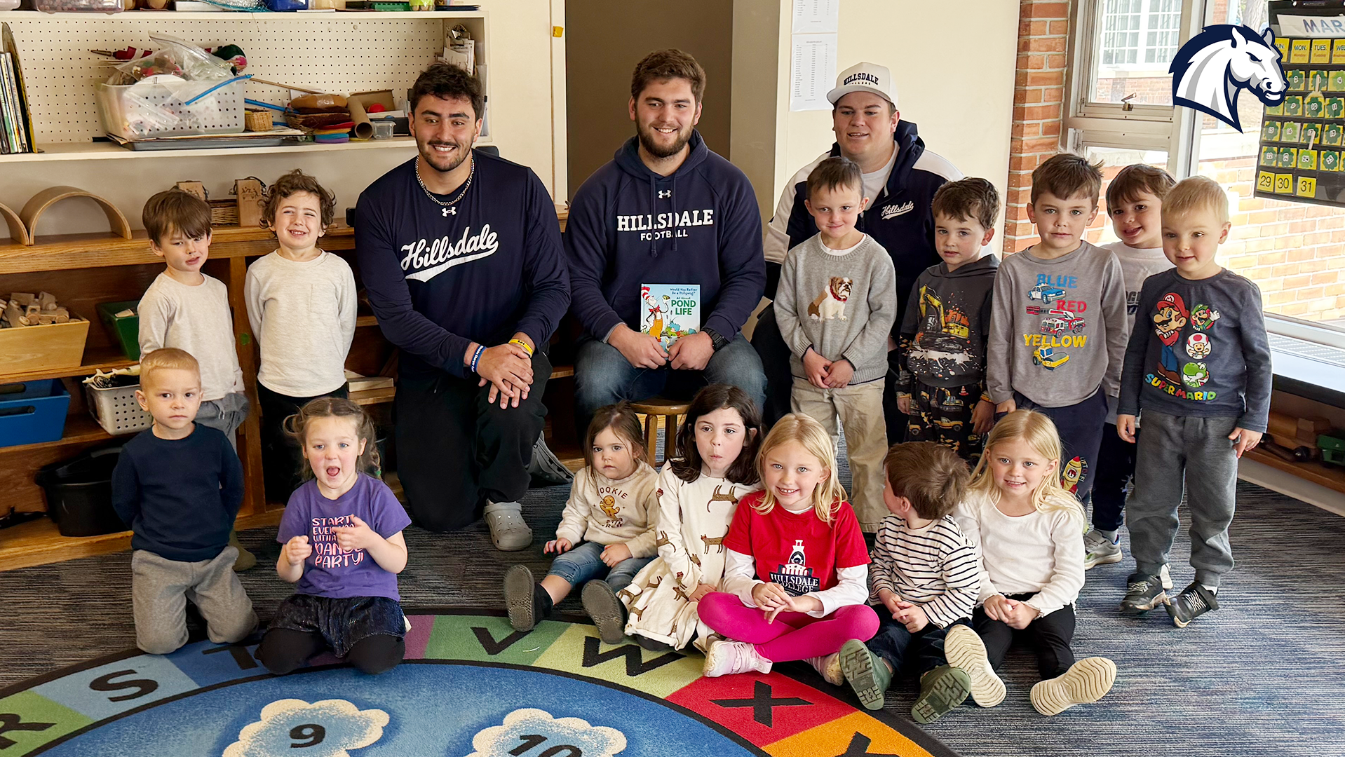 Hillsdale football players Jesse Medoza, Mason Moulton and Zac Affholter pose with a class at Mary Randall Preschool after reading a story book to the class on May 27, 2026.