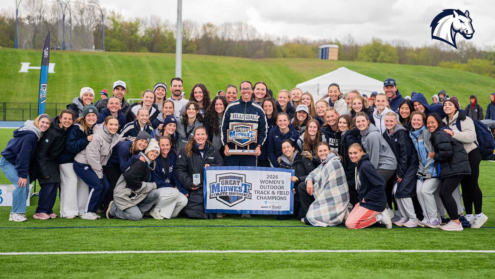 Hillsdale's women's track and field team poses with the G-MAC Championship trophy after winning the 2026 Outdoor title.