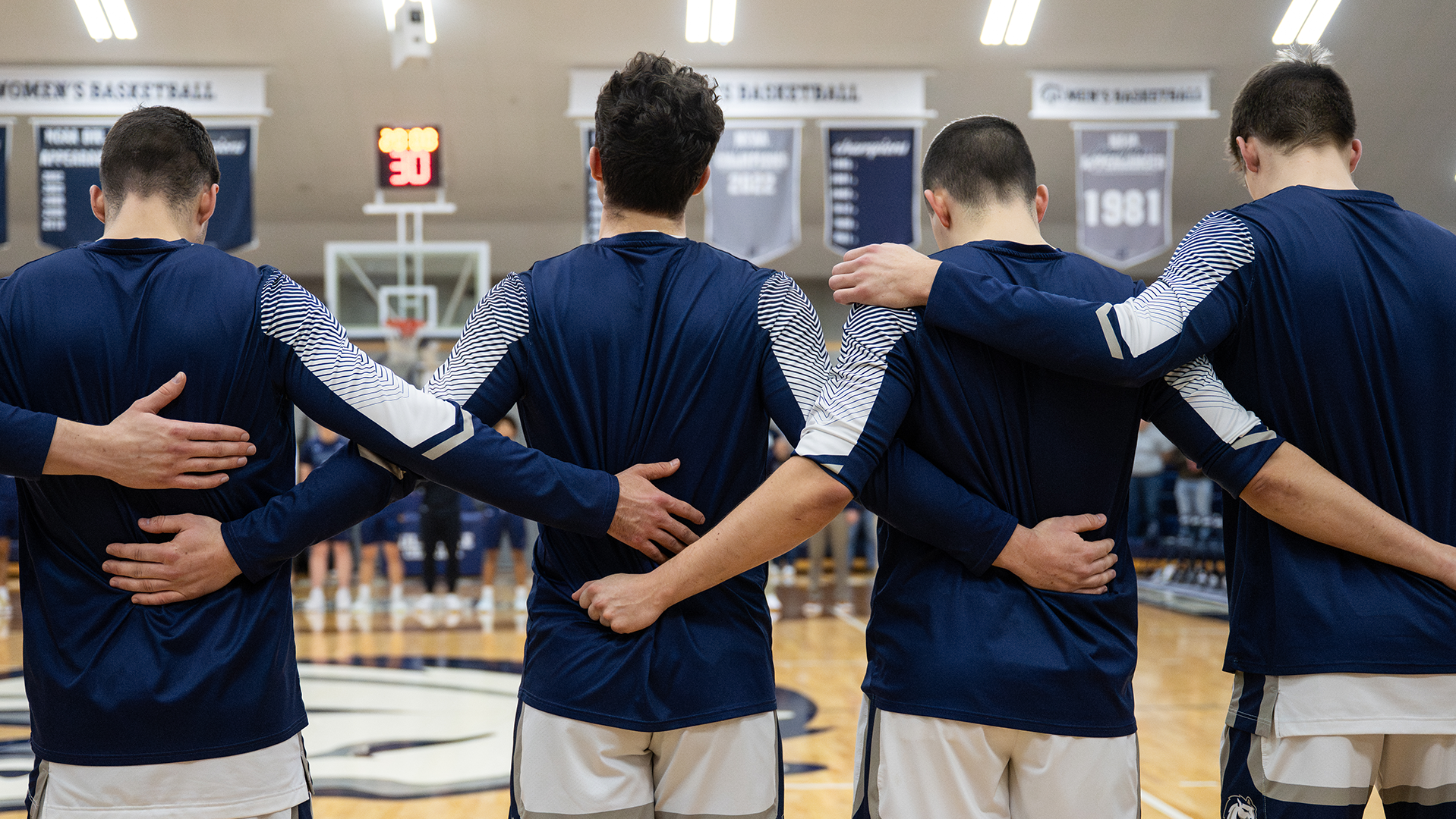 Hillsdale men's basketball players stand and face the flag before the national anthem.