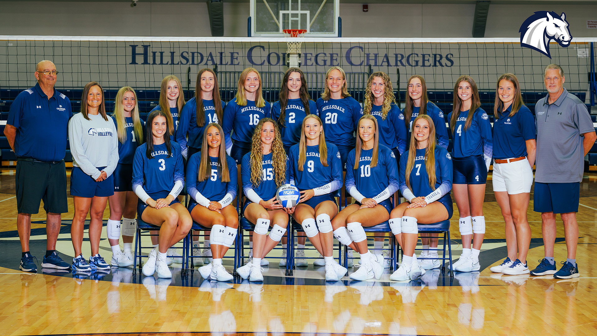 2025 Hillsdale College volleyball team photo, posed in Dawn Tibbetts Potter Arena in front of the net.