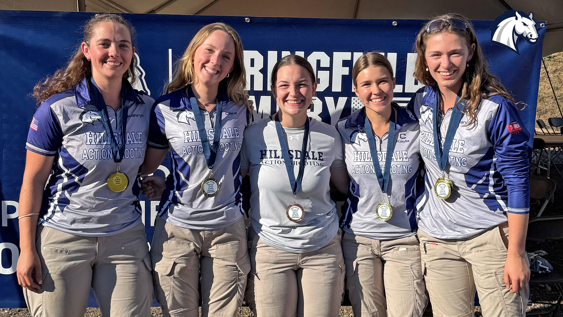 Five Chargers action shooting competitors pose with medals won at the 2026 USPSA Collegiate Championships.