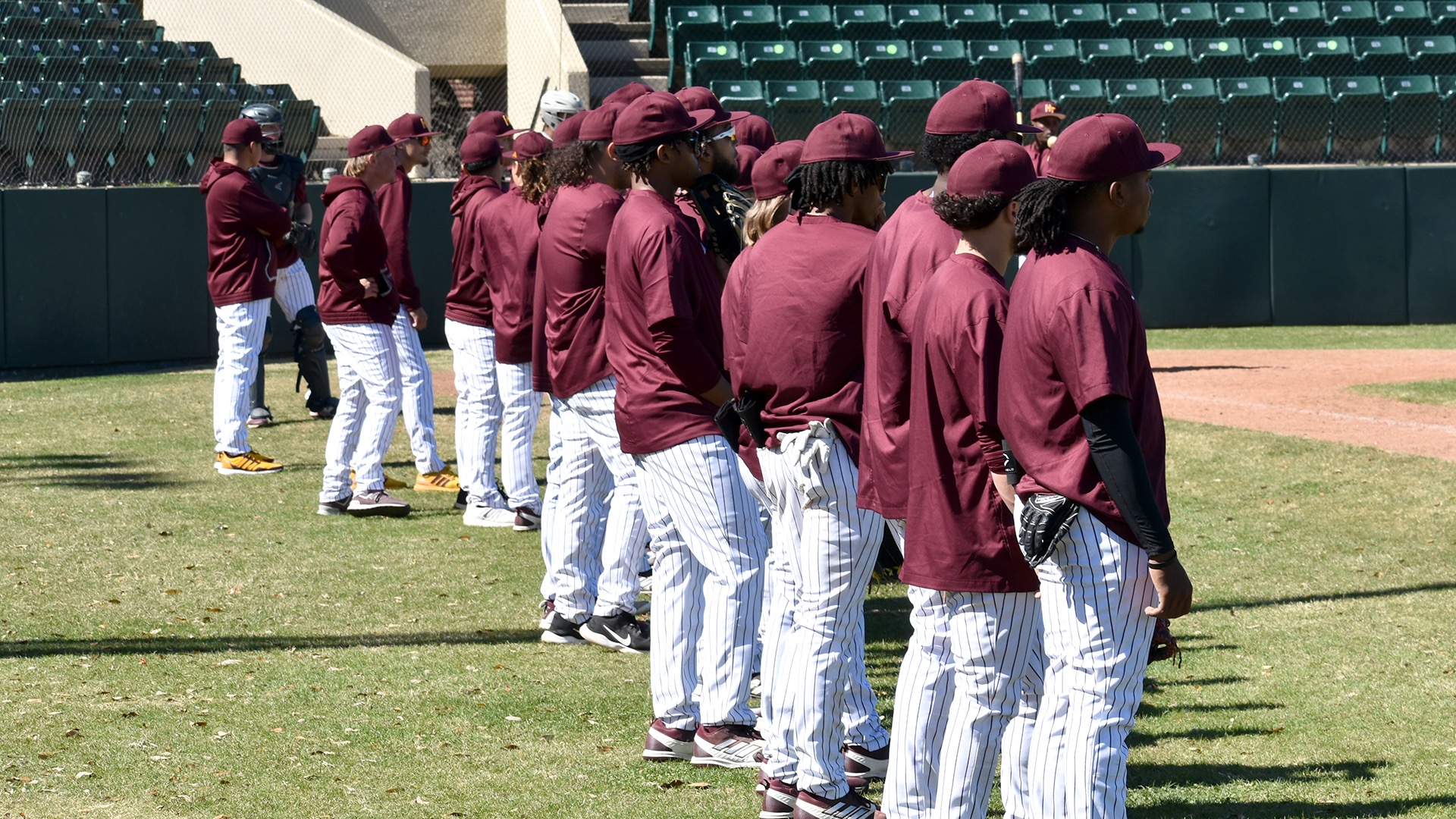 Members of HT's baseball team lineup along the first base line in a game earlier this season.