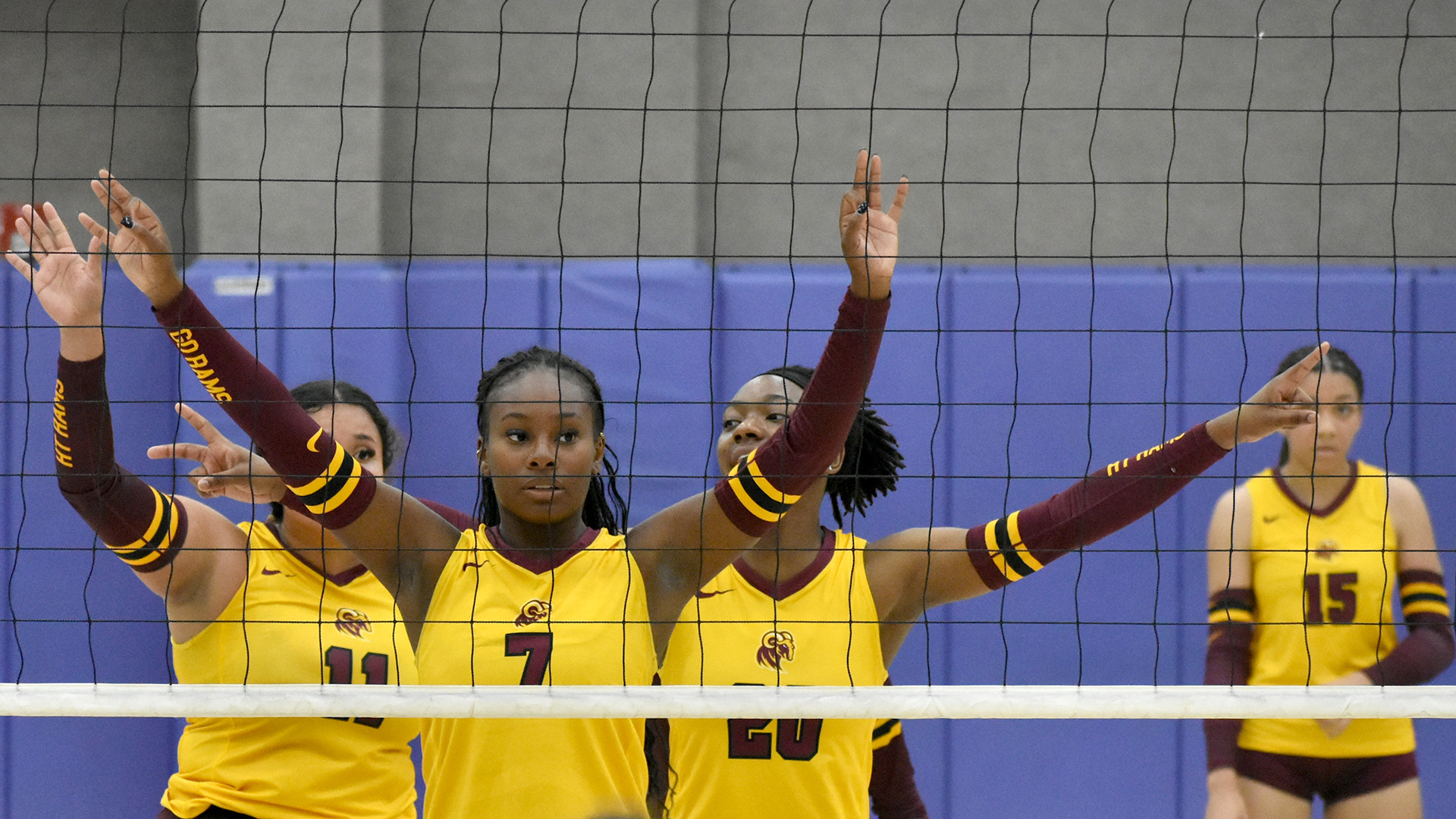 HT Volleyball players Chloe Gaytan, Amaiya Williams, and Lindsey Morris in the foreground with their arms raised waiting for a serve. Malaya Bennett can be seen in the background.