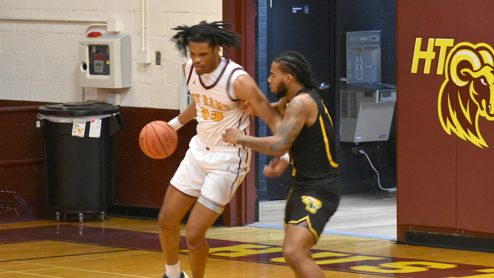HT center Kemondreon Cansler dribbles toward the basket while being guarded by Philander Smith's D'Andre Lockett