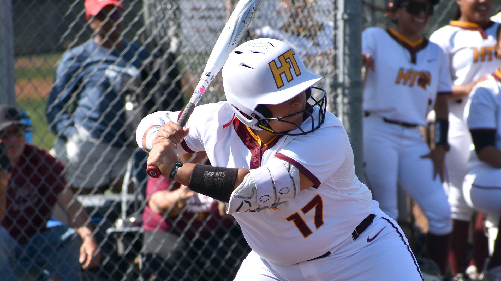 Aliyah Resendiz waits for a pitch while batting right-handed against Rust (Miss.). Some of her teammates in the dugout are visible in the background.