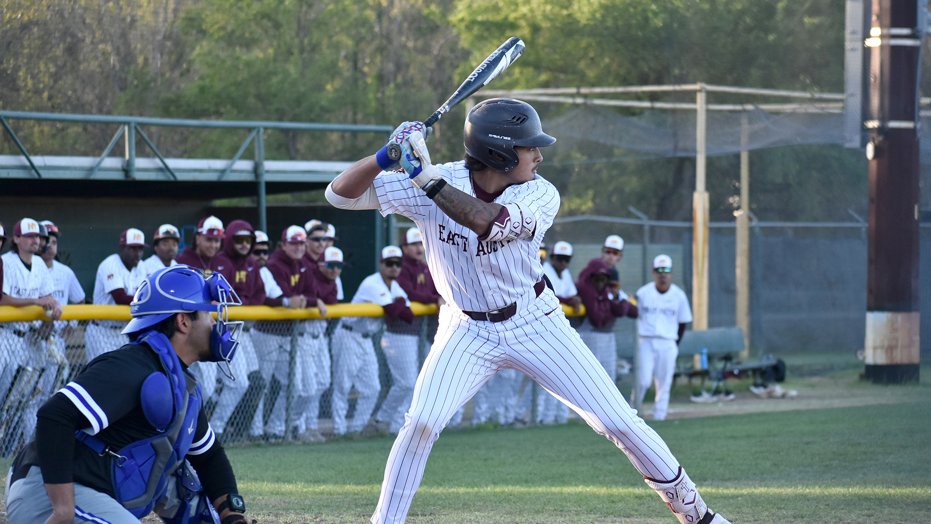 HT baseball player Noah Alvarez bats right-handed against Our Lady of the Lake. OLLU's catcher is visible in the bottom left of the picture, while Alvarez' HT teammates are visible in the dugout behind him.