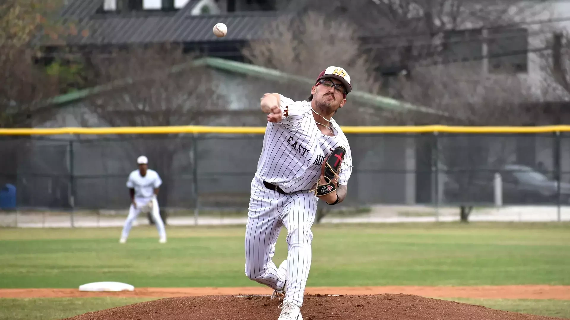 HT Baseball player Weston Bailey delivers a throw in a home game against Wiley. An HT outfielder is visible in the background.