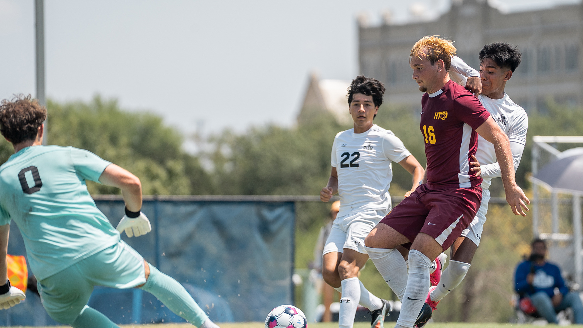 HT men's soccer player Boston Babiarz fends off two OLLU players as HT goalkeeper Chasen Hamsen gets to the ball