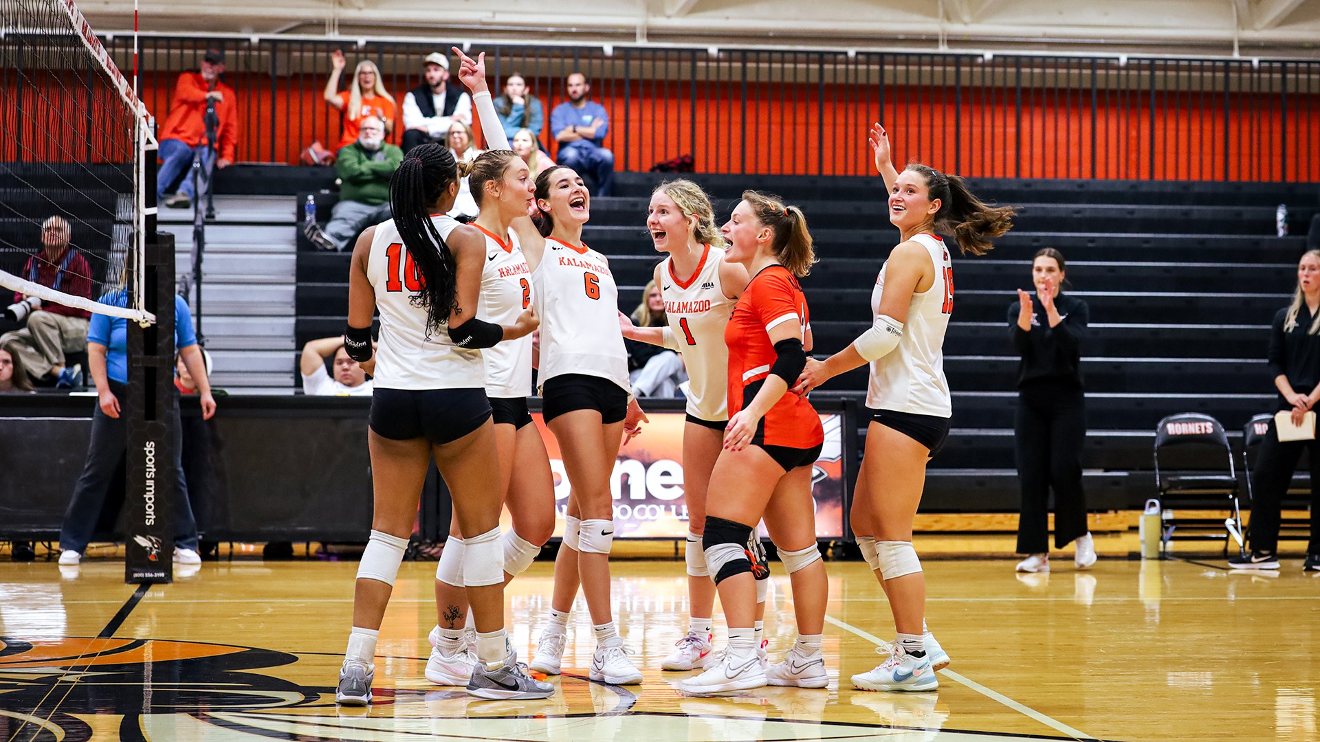 Kalamazoo College volleyball players celebrating on court