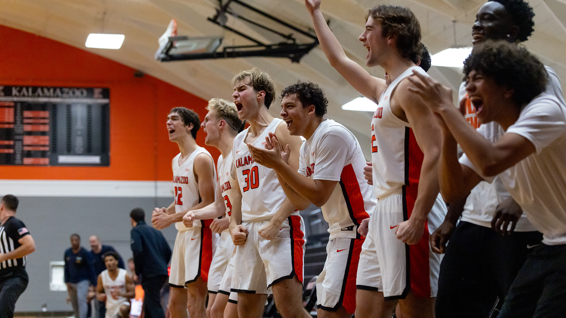 Kalamazoo College men's basketball players celebrate from the bench