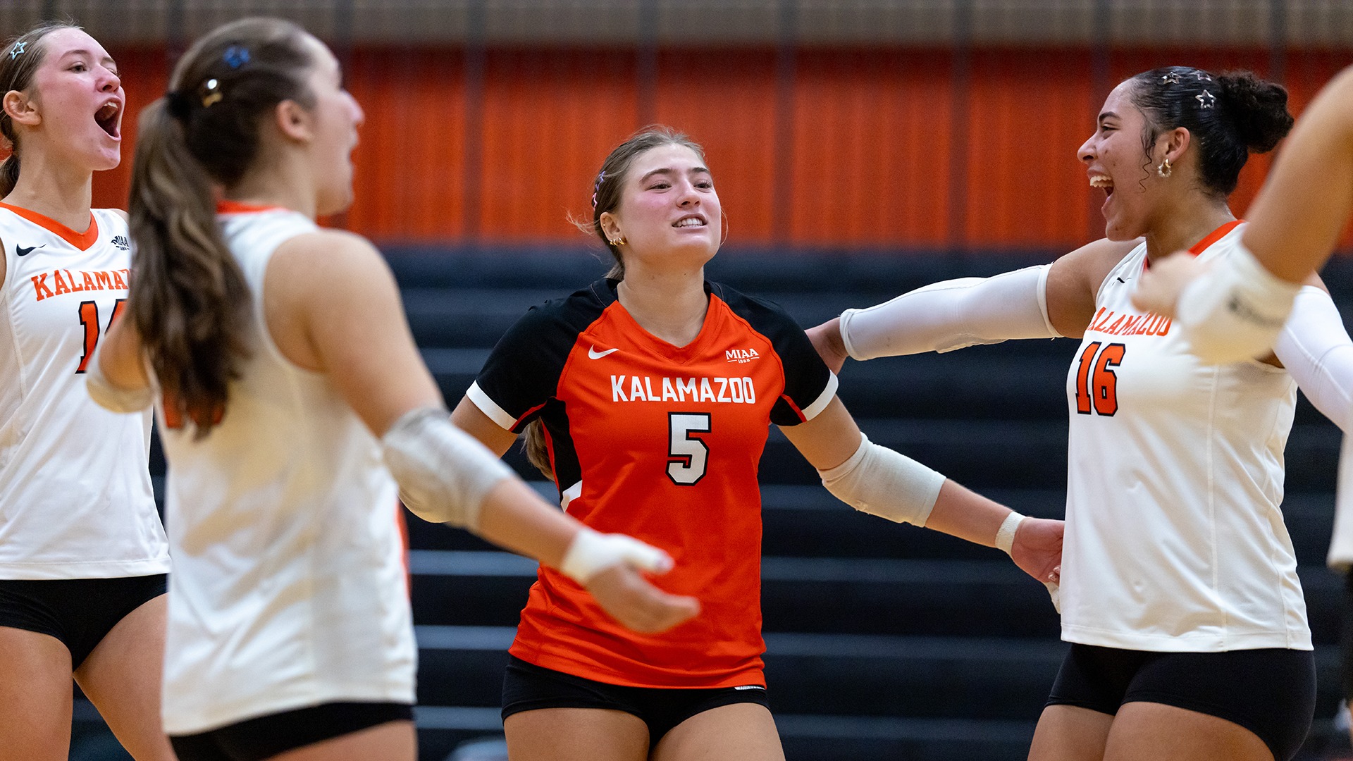 Kalamazoo College volleyball players celebrating on court