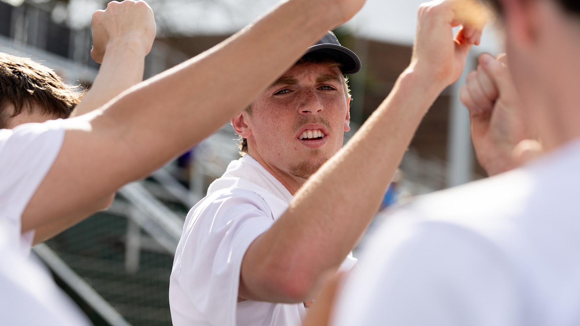 Cameron Crosby at the center of a Kalamazoo College men's tennis team huddle