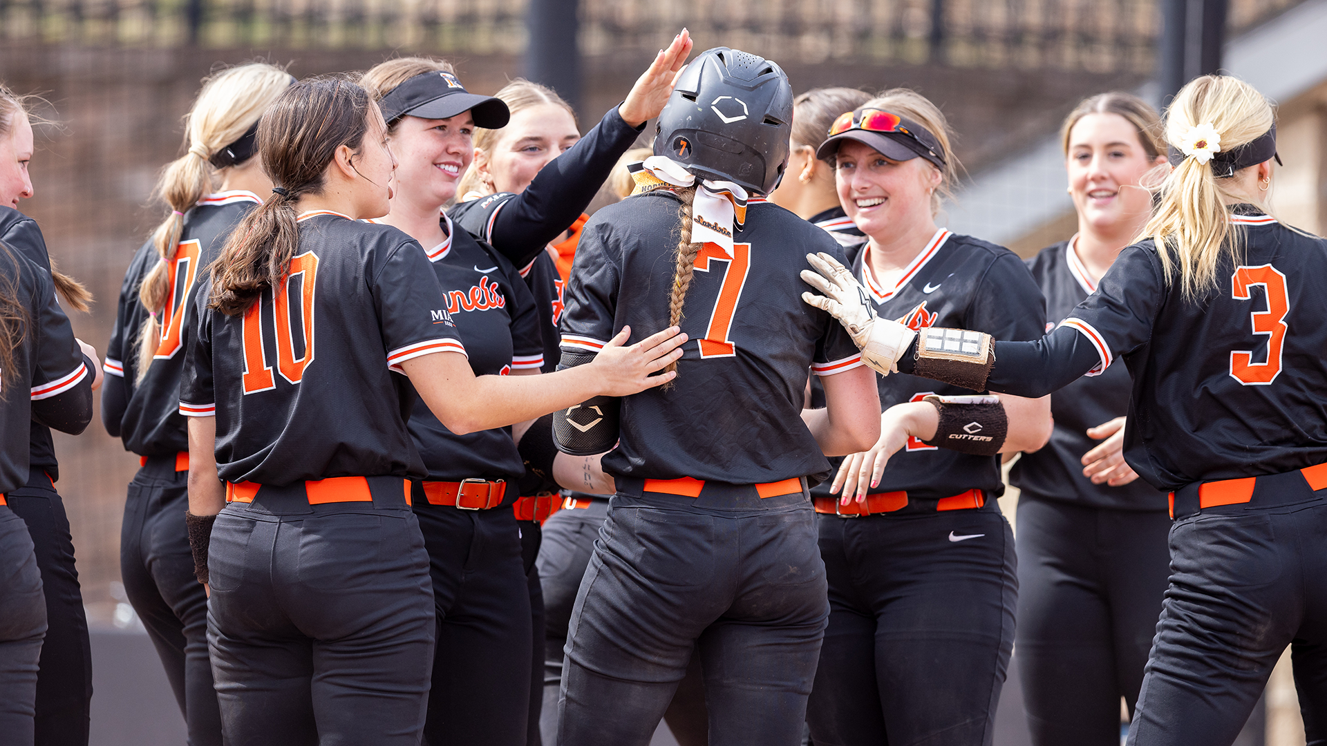 The Kalamazoo College softball team celebrating a home run hit by Landrie Fridsma