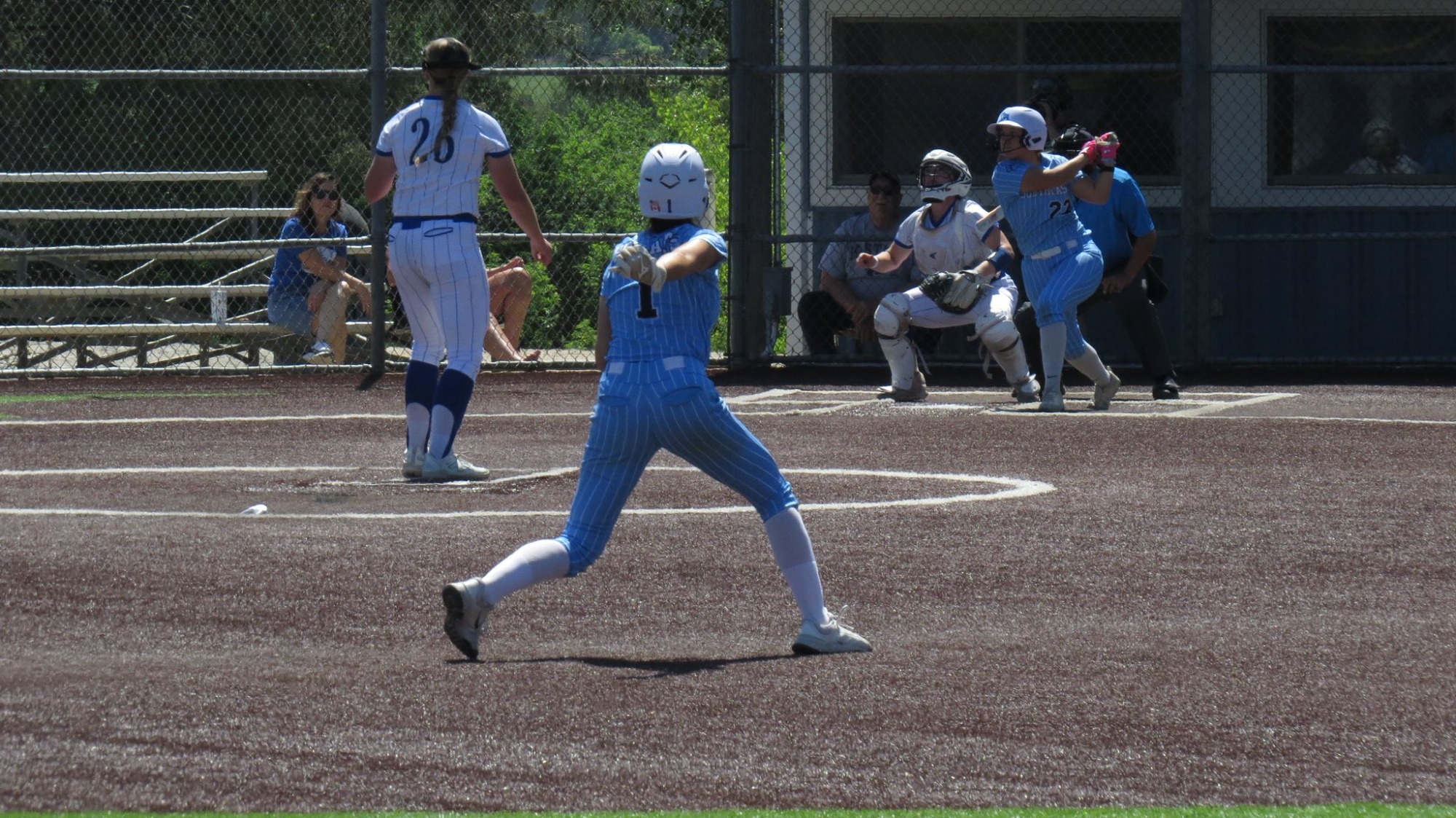 Lexi Paskach advances from second base while another SCC batter finishes her swing after a hit.