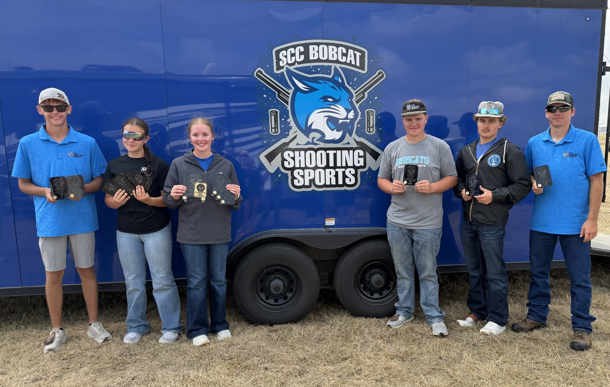 The SCC Shooting Sports team stands in front of their trailer holding their trophies from the Fort Hays Tech Freshman Shoot