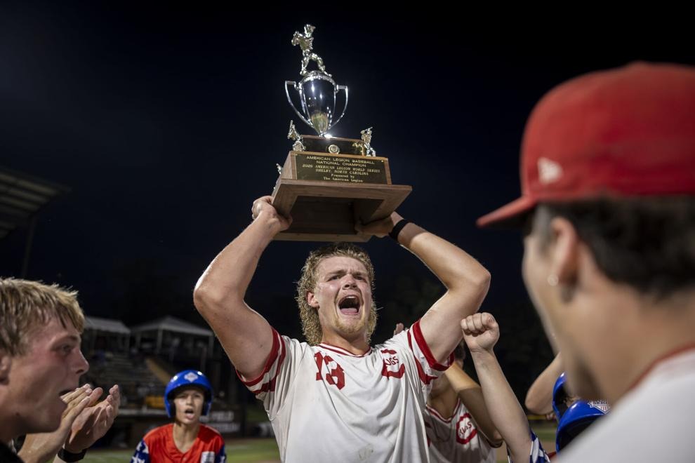 Greyson Bjorkman lifts the American Legion World Series trophy above his head as he celebrates with his Carpet Land teammates