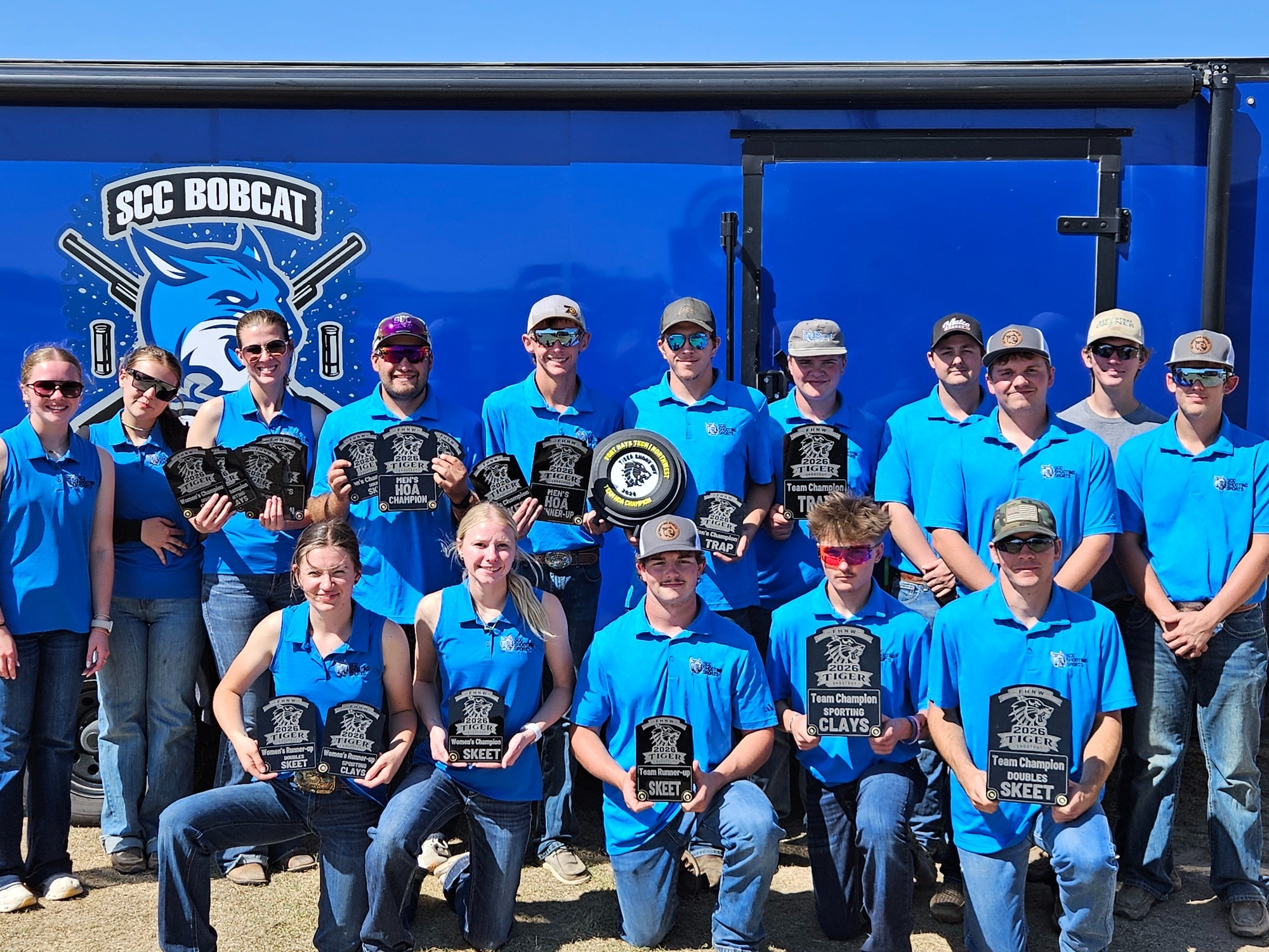 The SCC Shooting Sports team stands in front of their trailer, with many of them holding trophies.