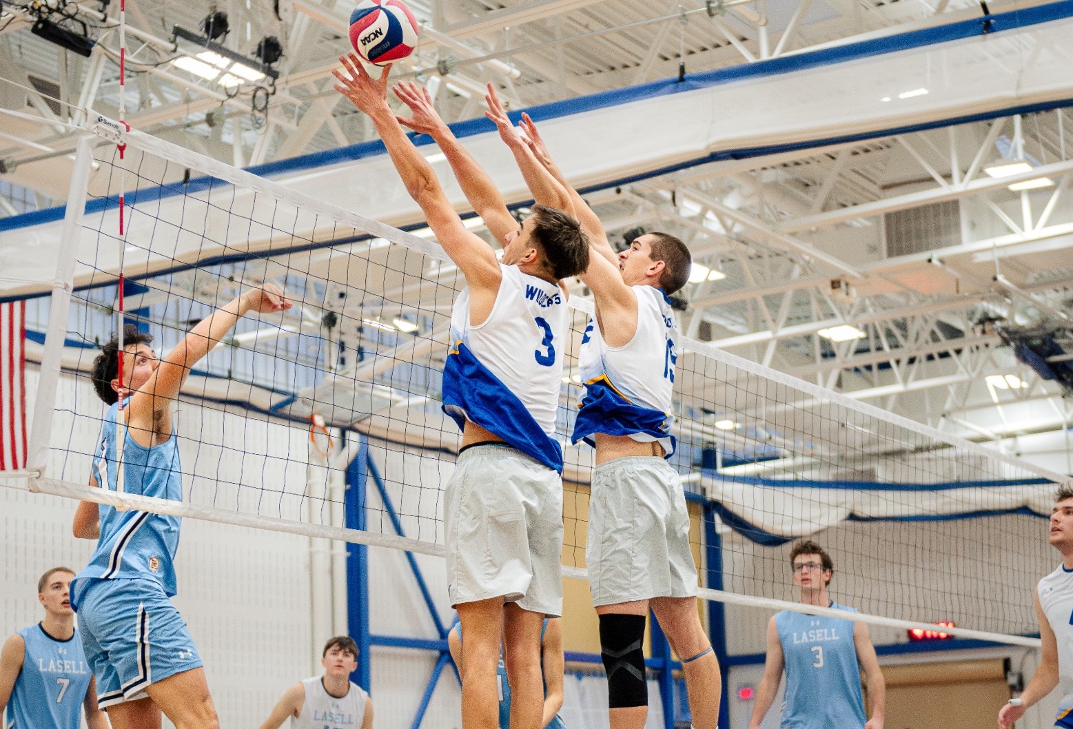 SUNY Poly volleyball players jump in an attempt to block incoming spike
