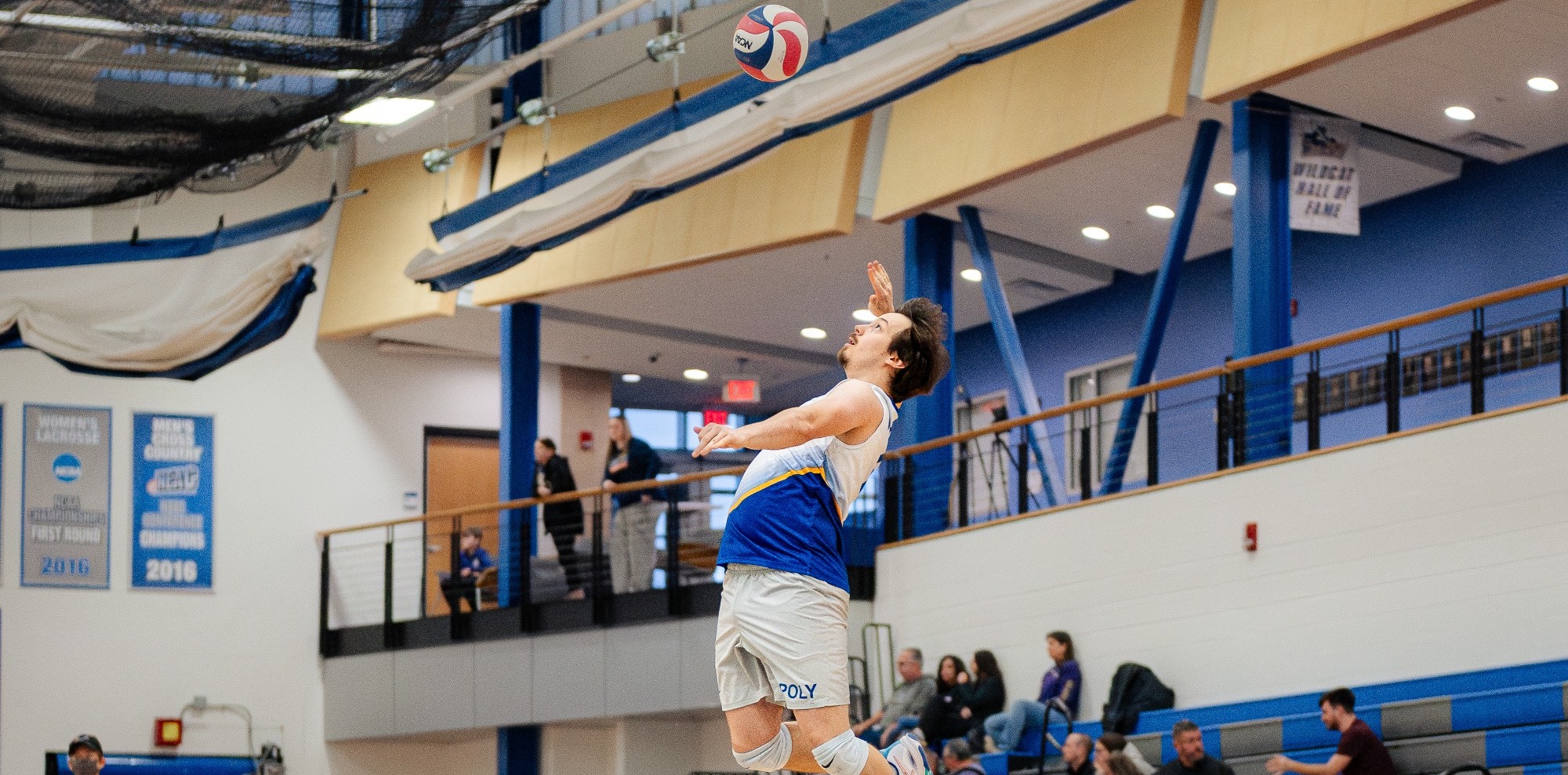 Men's volleyball player begins volley with a serve to opposing team