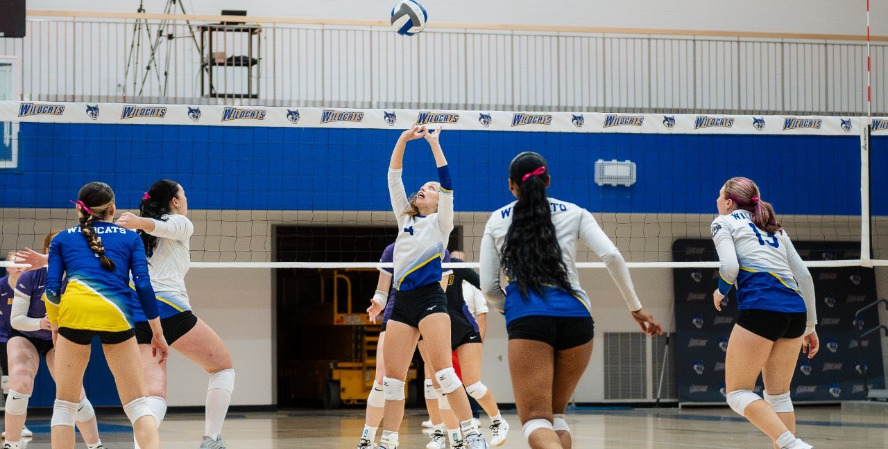 SUNY POLY women's volleyball player sets the ball for nearby teammate 