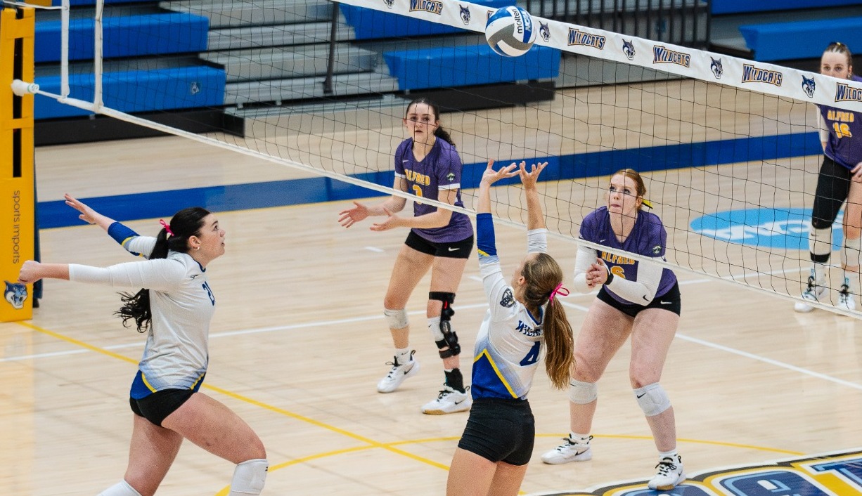 SUNY POLY women's volleyball player sets the ball for nearby teammate to spike