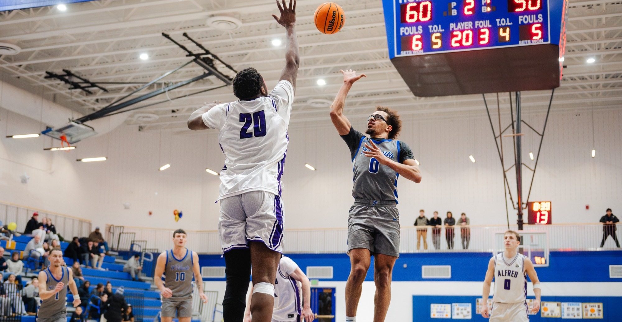 SUNY Poly men's basketball player attempts a floater over a defending opponent