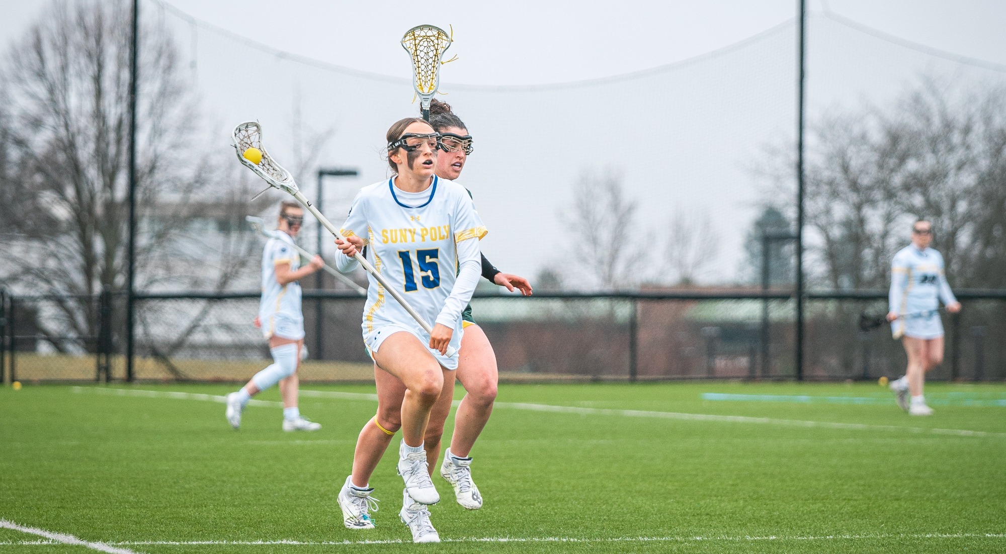 SUNY POLY women's lacrosse players sprints up the field in an attempt to clear the ball