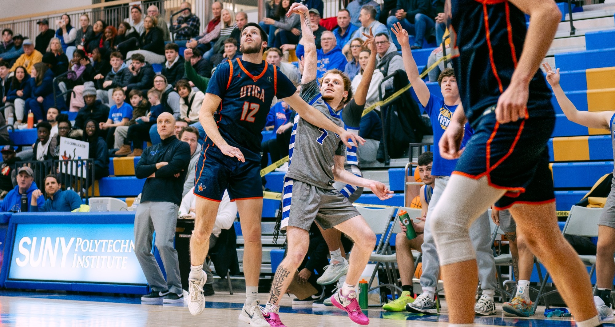 Men's basketball player follows through on his shot over a defender