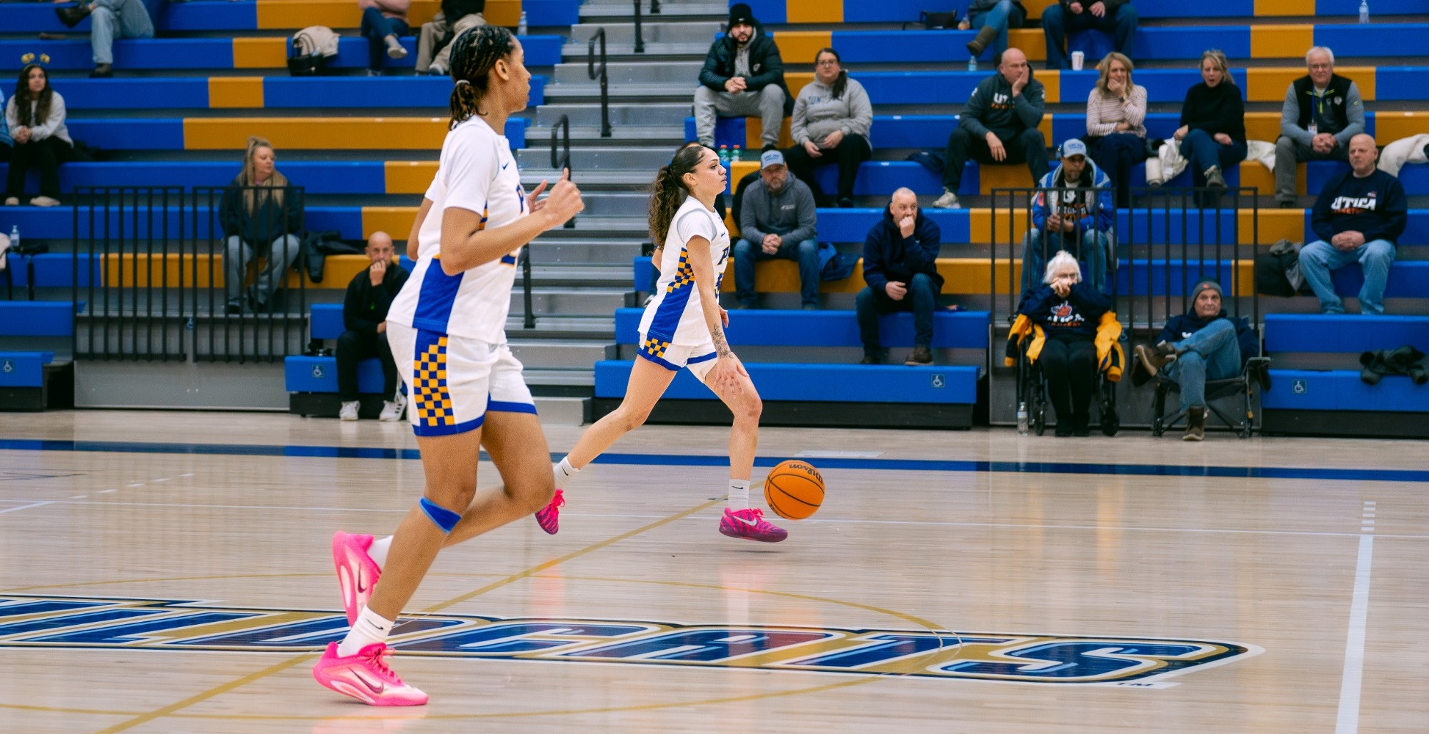 Women's basketball player dribbles ball past the half court