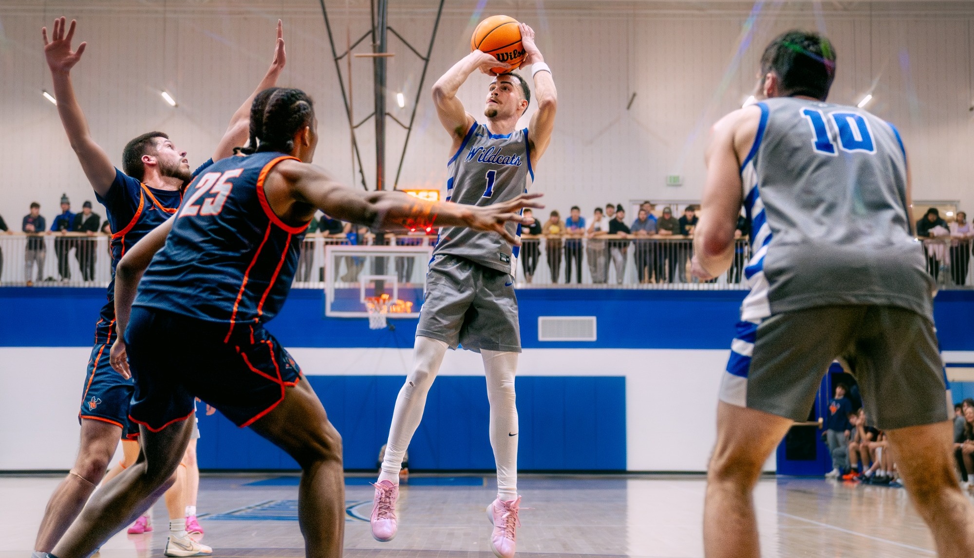 Men's basketball players rises over defender for a mid range jumpshot