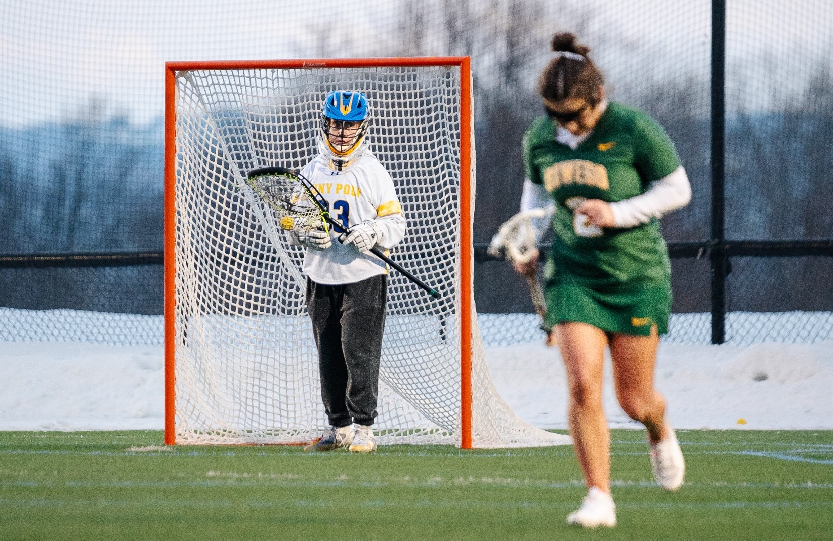 SUNY POLY women's lacrosse goalie waits for opponents to clear the field to pass the ball to teammates
