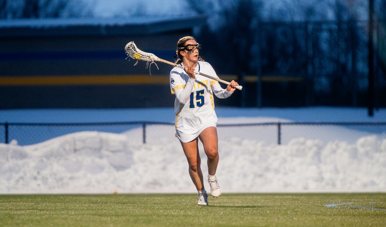 SUNY POLY Lacrosse player surveys the field as she makes an attempt to clear the ball