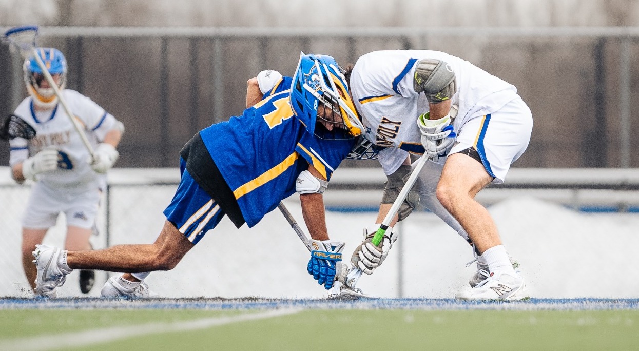 SUNY POLY Lacrosse player squares off with opponent in faceoff circle