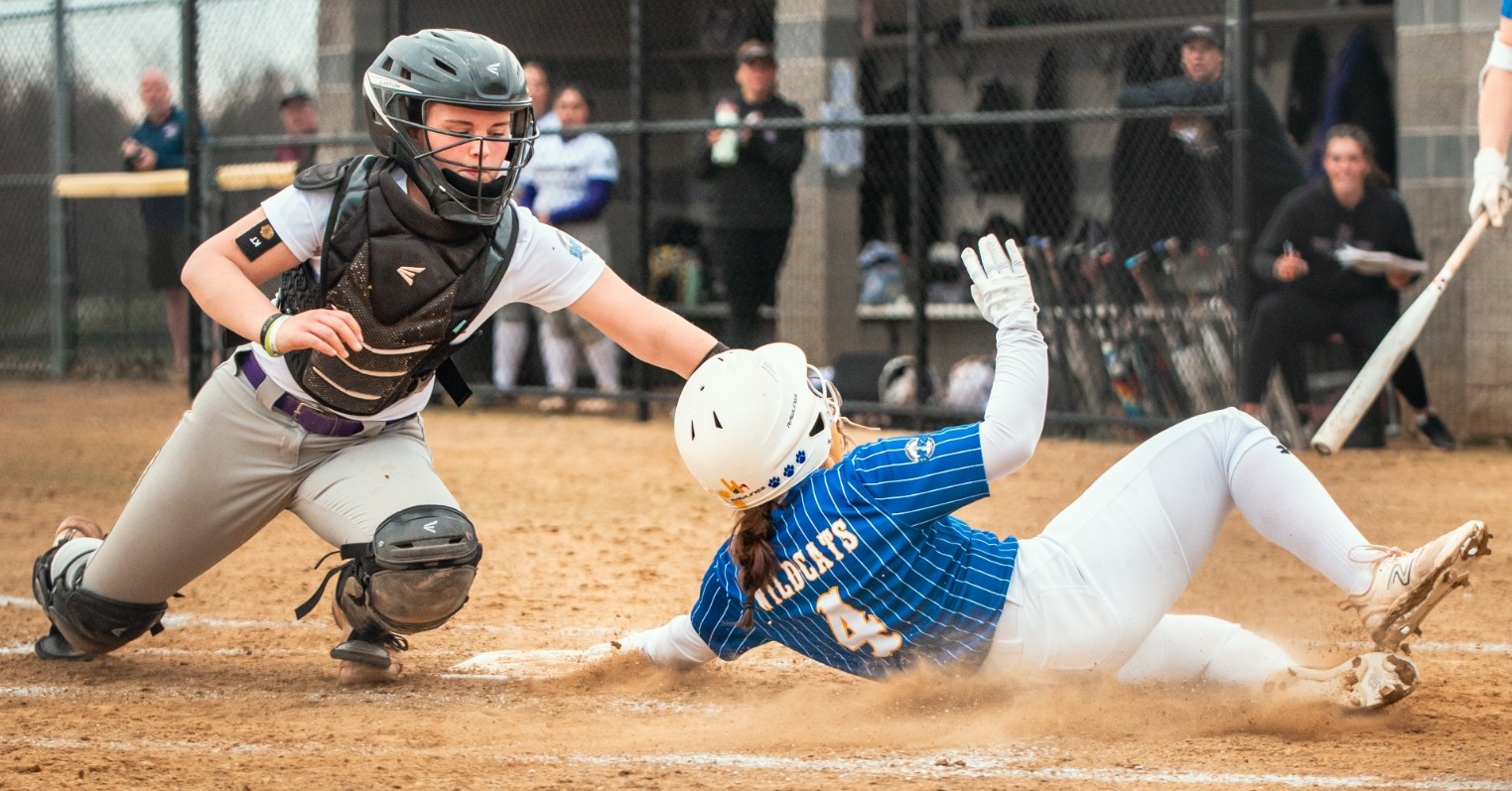 SUNY POLY softball player slides in under the tag to score a run