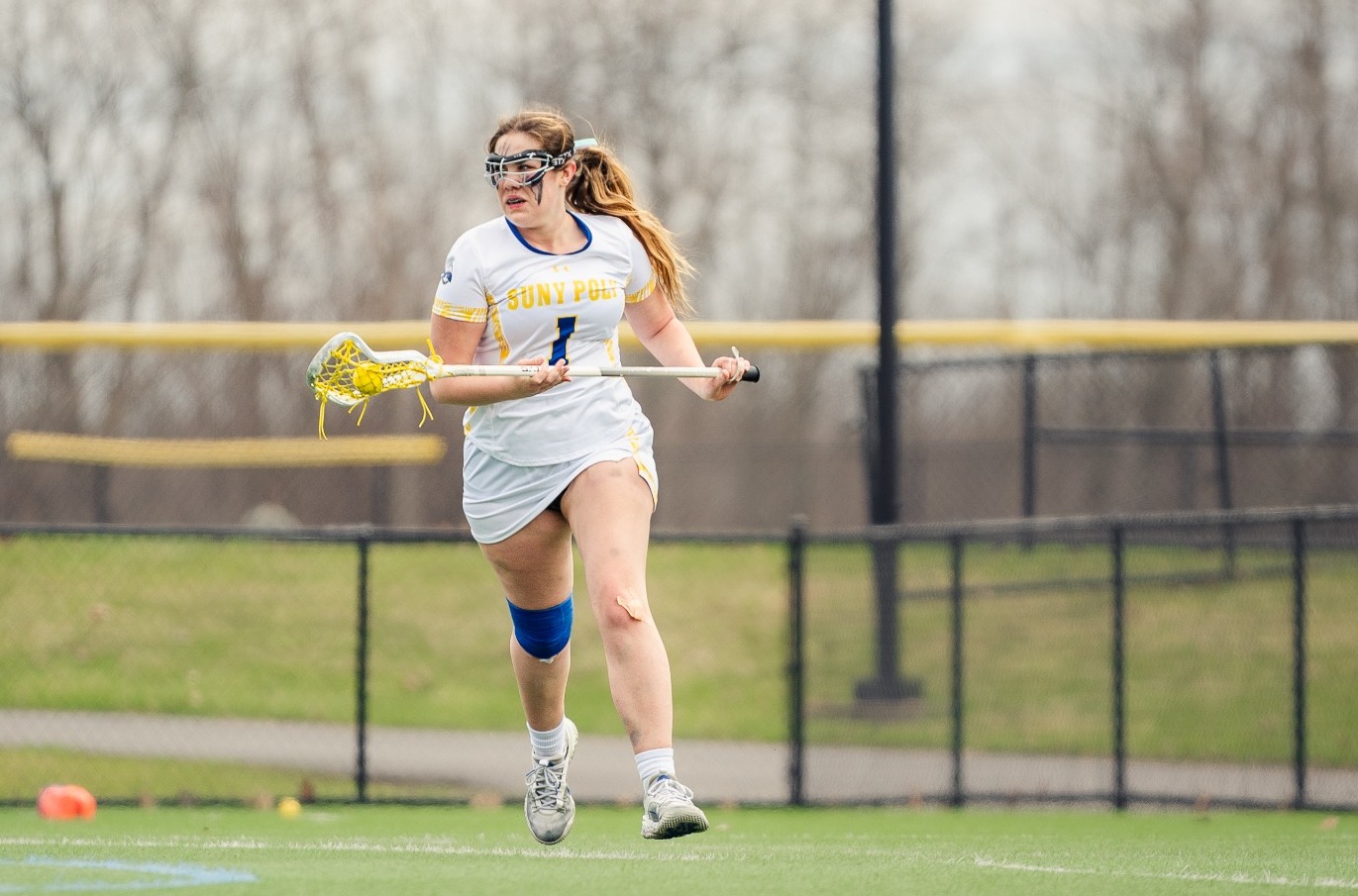 SUNY POLY Women's lacrosse player surveys the field from behind the net
