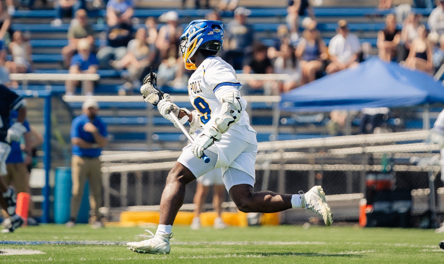 SUNY Poly men's lacrosse player runs the ball up the field in hopes of getting a successful clear