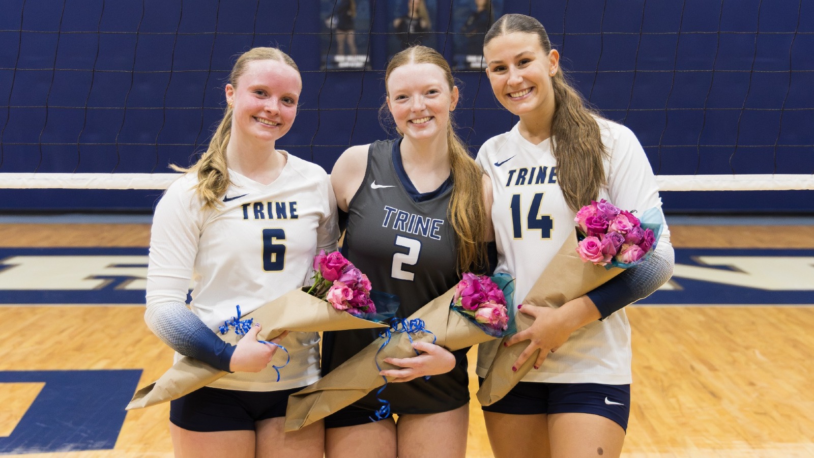 Trine Volleyball Seniors pose in front of the net