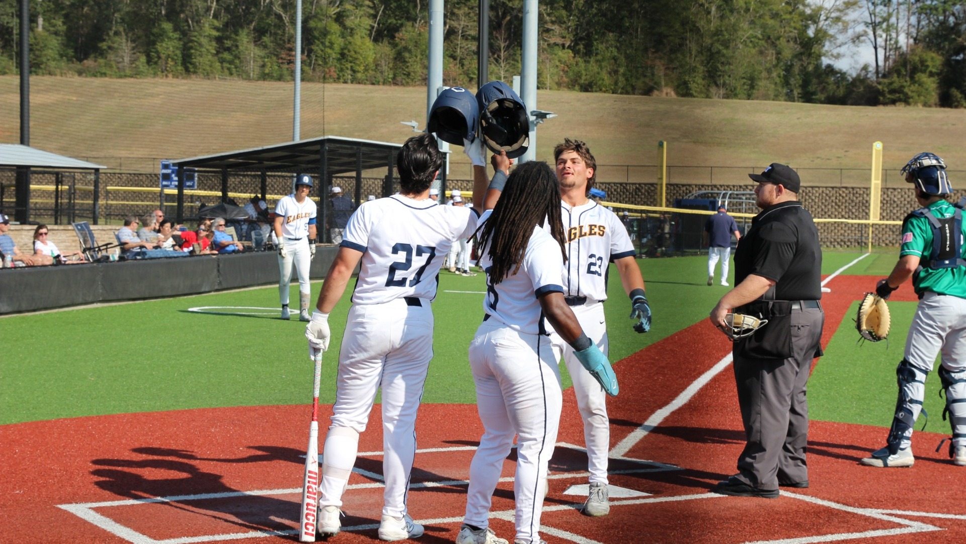 Eagle baseball players celebrating a home run at home plate.