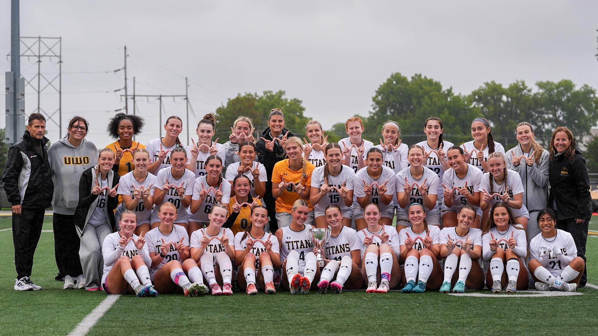 2026 Women's Soccer Group Photo, posing with the 151 Derby trophy after beating Dubuque