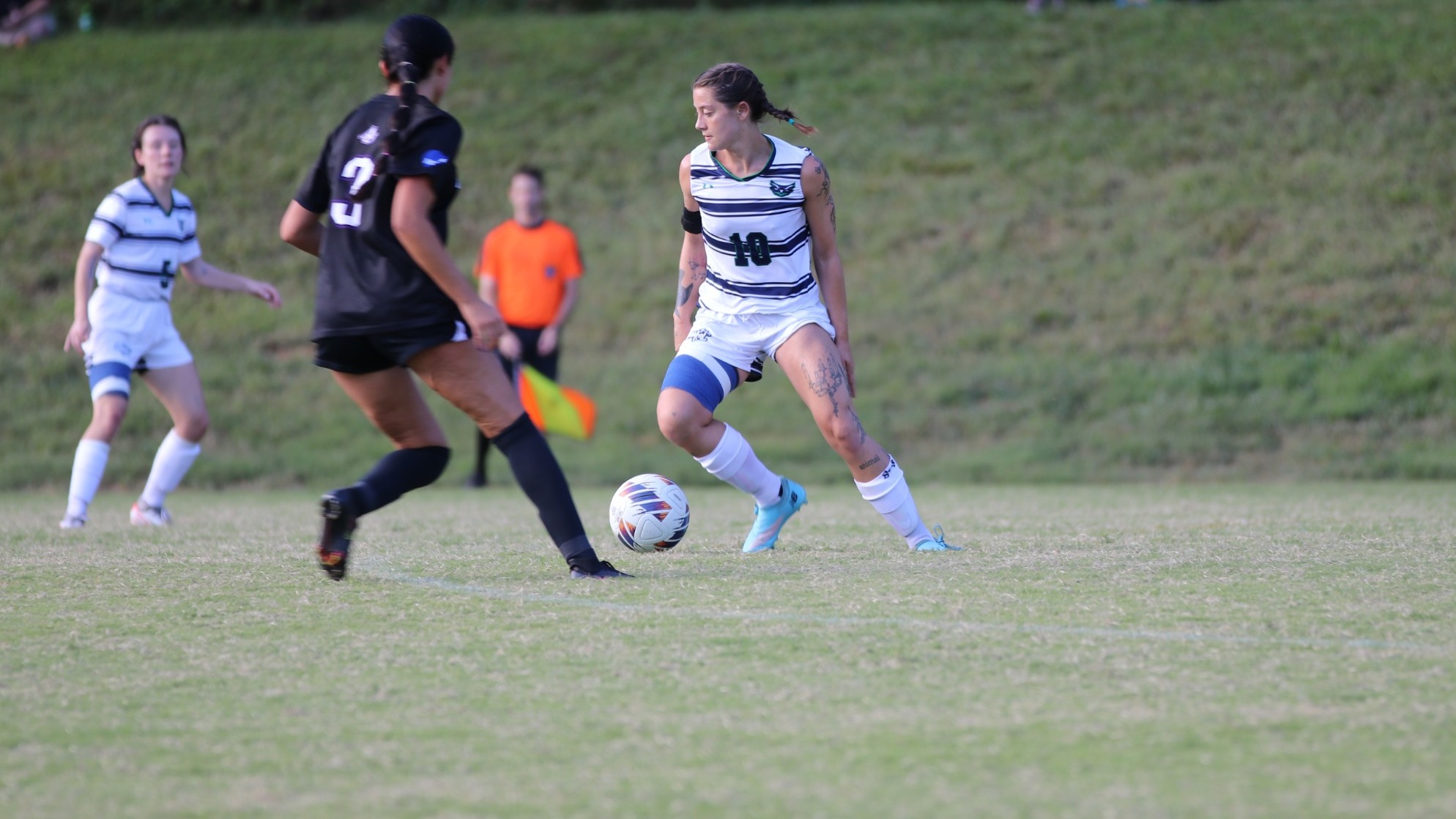 Women's Soccer Player, Kyra Collins kicks the soccer ball past her defender.