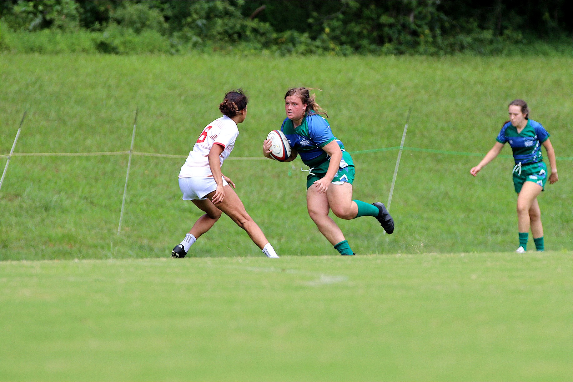 Hannah Johnson, a rugby player, runs down the field with the ball through her opponent.