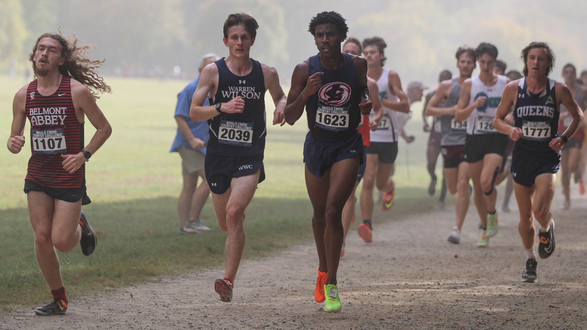 Cross Country runner, Henry Berta runs with a group of runners down a gravel pathway.