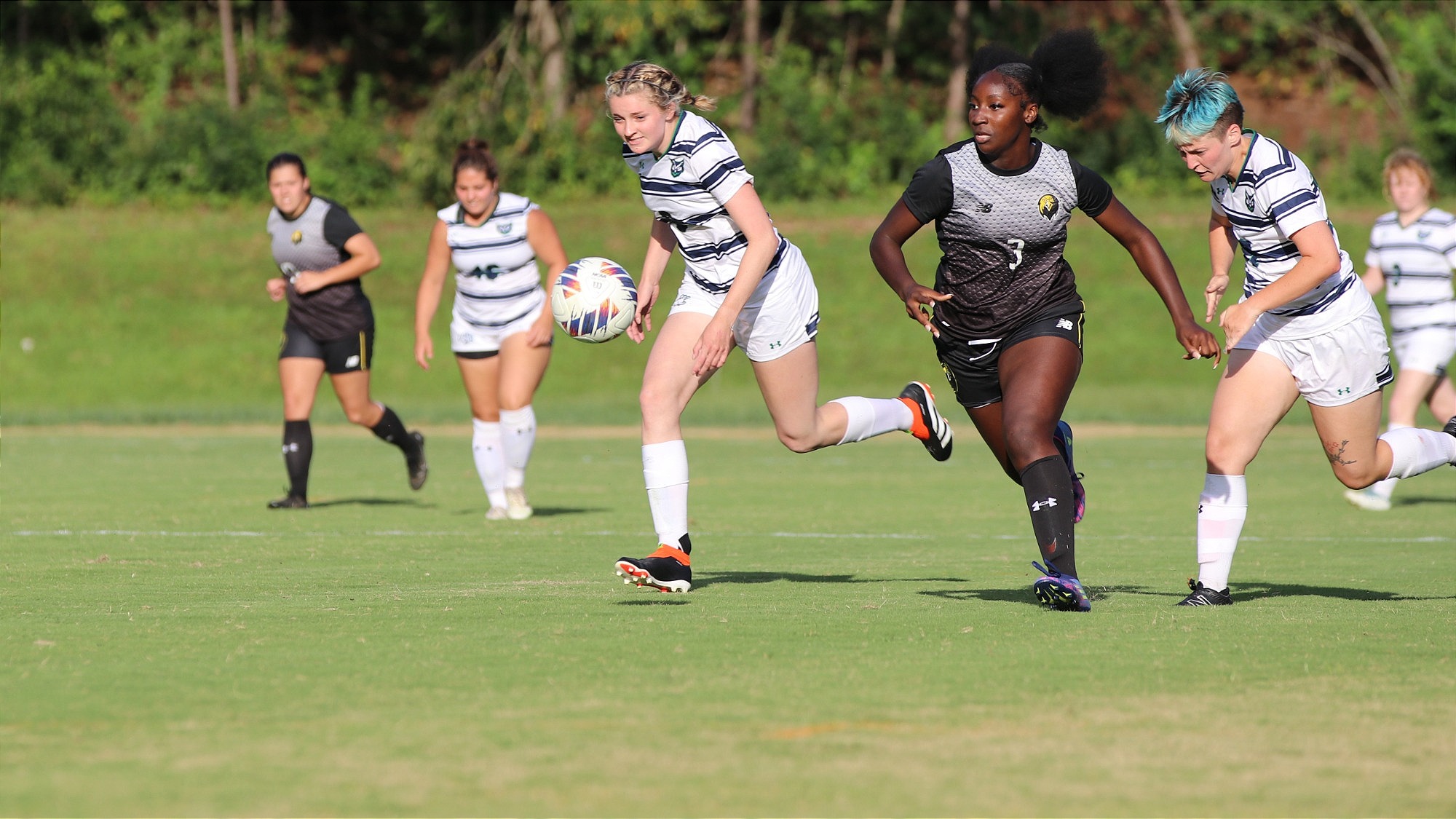 Soccer players, Cameron and Piper run with an opponent to get the ball.