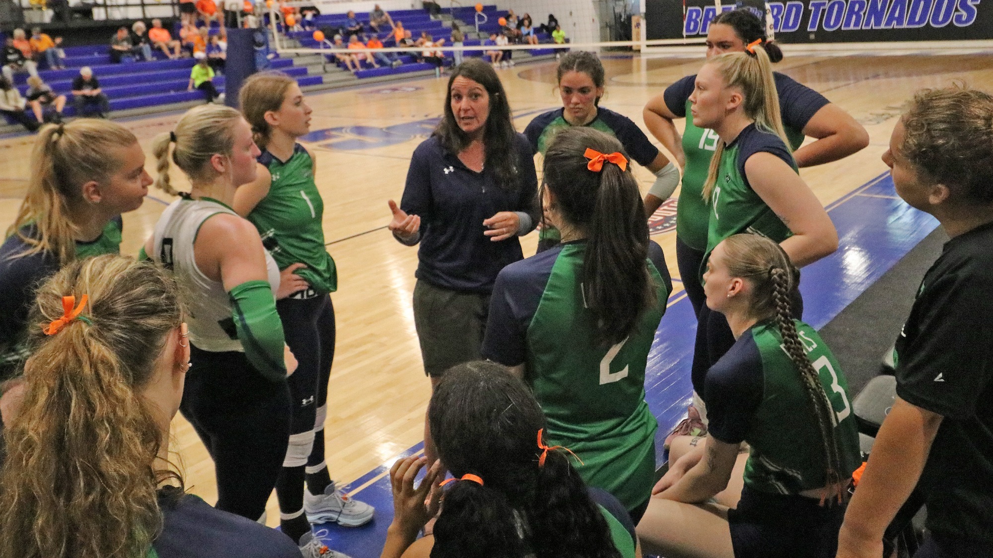 Kristy Kamer talking to her volleyball players on the bench during a game